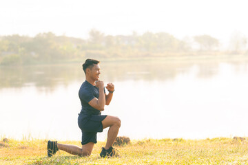 A young man in a T-shirt and shorts is stretching, with the sunlight shining in the background, creating a pre-workout training atmosphere.