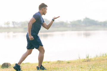 A young man in a T-shirt and shorts is stretching, with the sunlight shining in the background, creating a pre-workout training atmosphere.