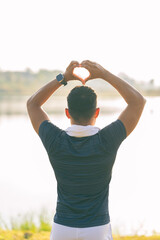 The young man made a heart shape with both hands above his head, with his back turned, and was in love. He made a heart shape with both hands.