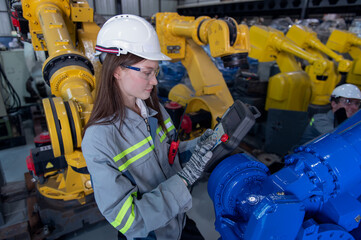 Engineer standing by robotic arm and operating machine in industry factory, technician worker check for repair maintenance electronic operation.