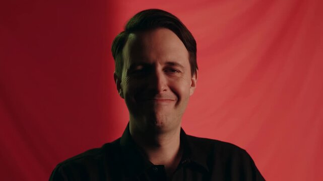 Man smiling against red background with dynamic lighting changes