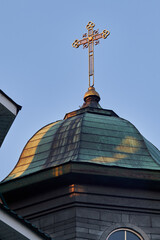 Golden Orthodox cross atop aged church dome against clear blue sky