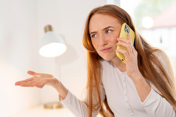 Woman speaking on a yellow phone with a frustrated expression while gesturing with her hand