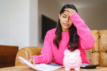 Woman sitting on couch looking at papers with a piggy bank in front of her