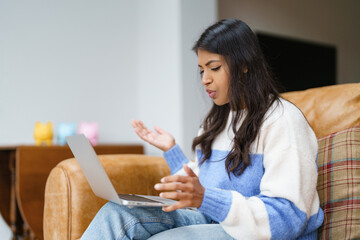 Woman using laptop in living room while expressing frustration over a task