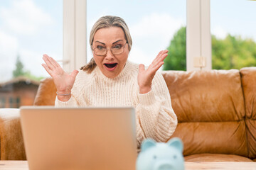 Woman shows excitement while using laptop at home in the afternoon