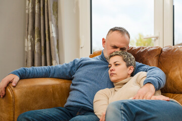 Couple sitting together on a couch while sharing a quiet moment in their home