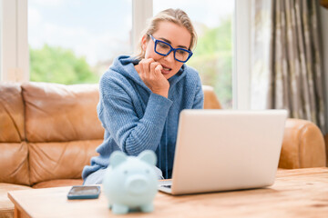 A woman is working at a table with a laptop open in front of her