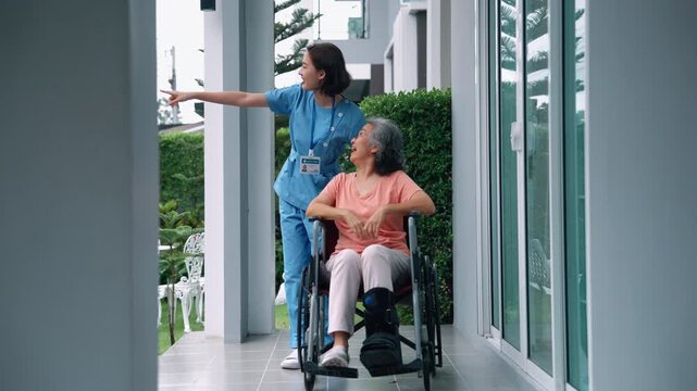 Female caregiver assisting an elderly woman in a wheelchair along a residential walkway, symbolizing mobility support and outdoor senior care.

