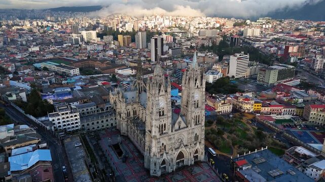 Aerial drone footage of the Basilica del Voto Nacional, one of the most iconic landmarks in Quito, Ecuador. Neo-Gothic architecture rising above the historic city, surrounded by urban landscape and An