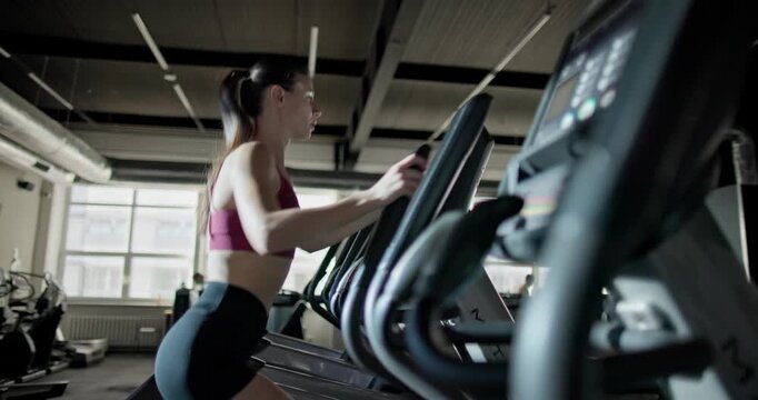 Young beautiful woman in sportswear doing cardio workout and exercises on stepper machine in the gym