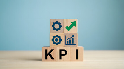 Wooden blocks displaying KPI business strategy process improvement and growth icons on a light wooden surface with a soft blue background