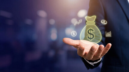 Businessman holds glowing money bag icon, symbolizing financial growth and investment opportunities. background is blurred, highlighting focus on concept of wealth and success