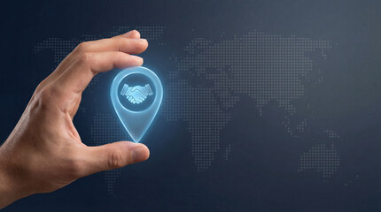 Hand holding digital location pin with handshake icon, symbolizing global business connections against world map background. image conveys partnership and international collaboration
