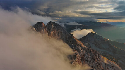 Amazing rocky mountains in clouds at sunset