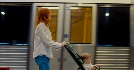 Young mother walks with her baby on subway platform during urban travel