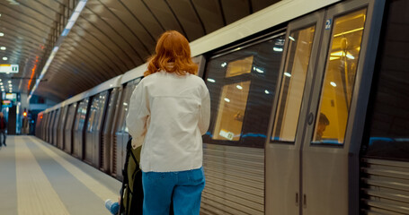 Young mother with baby waits on subway platform in urban transit