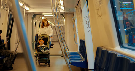 Young mother travels on subway with her baby in stroller during city journey