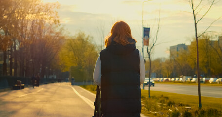 Young mother with baby stroller enjoying a sunny walk down the street