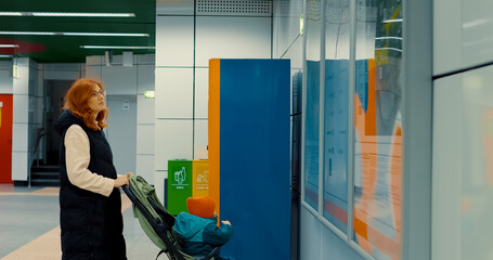 Young mother checks subway information boards with baby in stroller