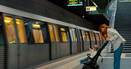 Woman with child waits on subway platform during urban travel
