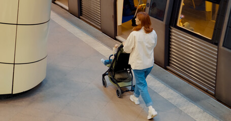 Mother and child navigating subway platform with baby stroller on a busy day