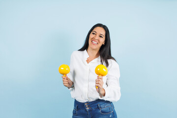 portrait of adult mexican woman dancing and holding maracas on blue background in Mexico Latin America, or Latina middle aged brunette female 