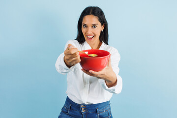 portrait of adult mexican woman eating and holding a bowl on blue background in Mexico Latin America, or Latina middle aged brunette female 