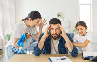 Stress and despair of father over chaos and crazy noise at home, man sitting at table with burnout...