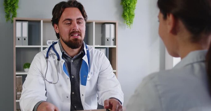 Doctor greeting patient with handshake at start of healthcare consultation in hospital. Male friendly general practitioner and woman shake hands before discussion of diagnosis and medical treatment