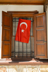 Turkish flag on the window of a wooden Ottoman mansion. Traditional Ottoman house in Antalya. Old wooden mansion of Turkish architecture.