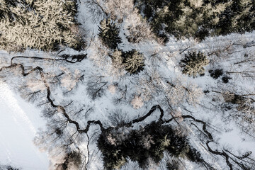 Winter rural landscape from a drone. Snow, stream, and forest.