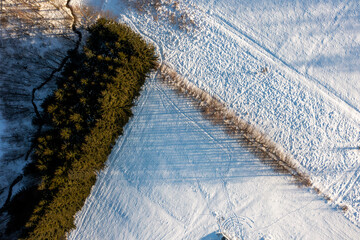 Winter rural landscape from a drone. Snow, stream, and forest.
