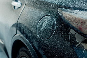 Frozen fuel tank cap on car body in winter
