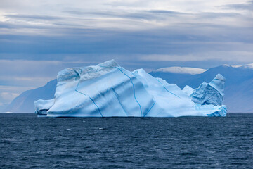 Iceberg with blue seams in the cold, blue waters of the Arctic Ocean at Bontekoe Island, Northeast Greenland National Park.