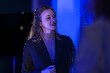 Female data scientist analyzing digital statistics on interface. Tech expert explaining software performance graph to team in modern blue control room.