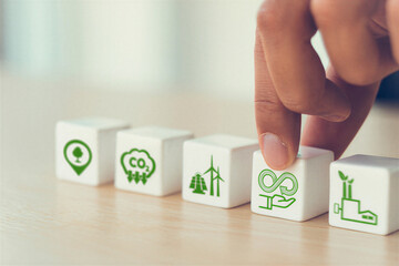 Hand placing a block with an eco friendly symbol on a wooden table with other blocks