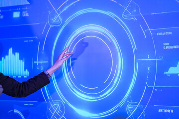 Business executive presenting digital strategy on large blue screen. Female leader pointing at circular data chart during corporate meeting presentation at night.