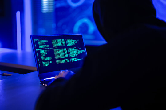 Professional cyber security specialist monitoring network safety. Tech expert in hoodie analyzing code to protect digital system from hacker threats in dark office - Powered by Adobe