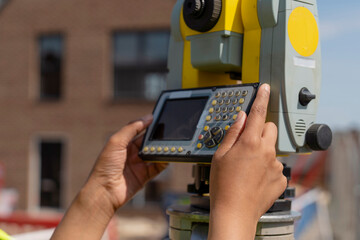 Close-up of Female builder land surveyor measuring on construction site using survey equipment to check work progress