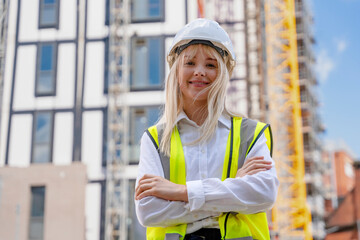 Portrait of young builder woman posing in front of construction site © Iryna