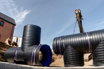 Construction crew uses crane to lift large plastic pipes at a building site