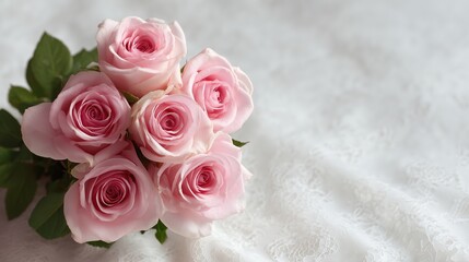 Soft pink roses bouquet arranged on a delicate lace surface with soft light