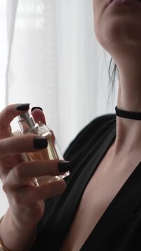 beautiful woman in black satin robe and choker spraying perfume on her neck. close-up, beautiful lips, mysterious shot. boudoir, getting ready for a date. elegance