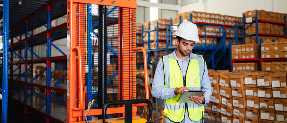 Professional warehouse workers using digital tablet with forklift and pallets. Logistics team management, inventory control, and industrial supply chain concept.