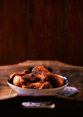 Fried chicken wings with potatoes on a rustic background. Soft focus.
