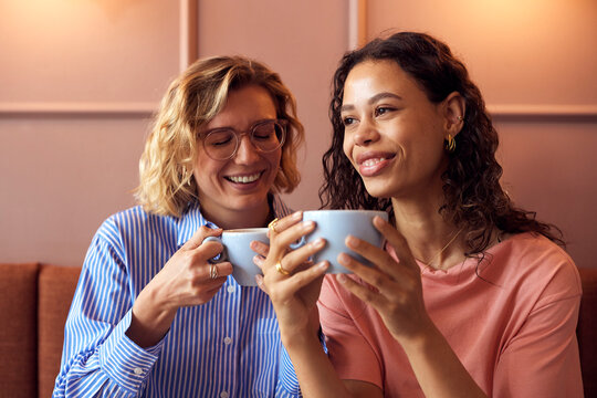 Friends share a warm moment in a cozy cafe, sipping coffee and enjoying conversation