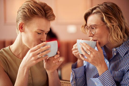 Two women enjoy coffee together in a cozy cafe, sharing a warm moment