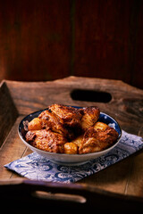 Fried chicken wings with potatoes on a rustic background. Soft focus.
