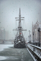 Beautiful ancient sail ship moored on the embankment of frozen Motlawa river in Gdansk